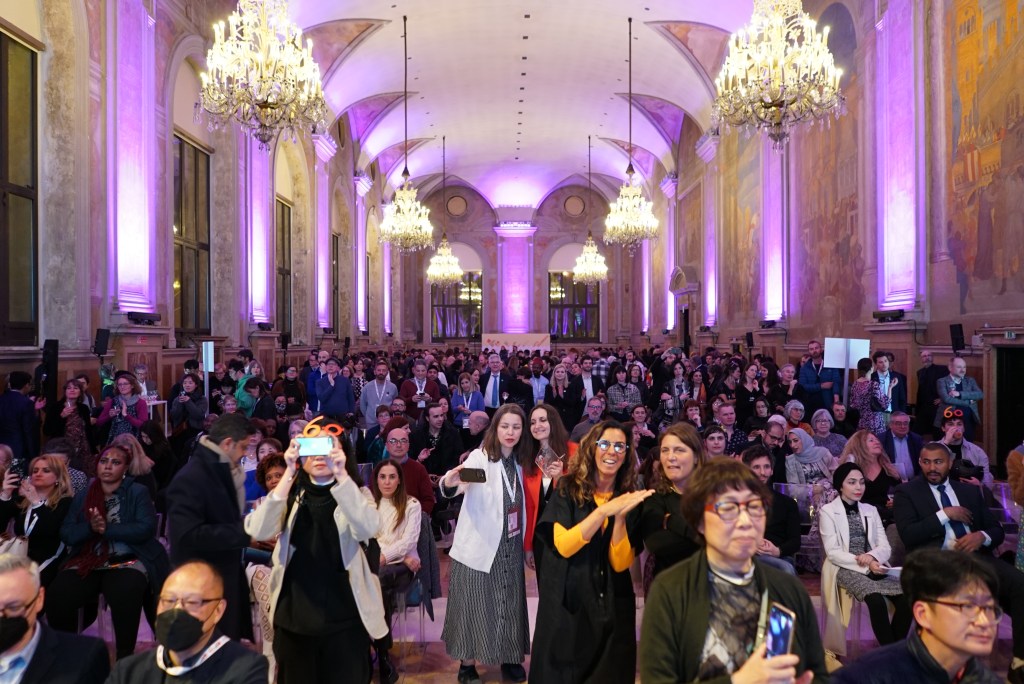 Pubblico riunito in una sala per eventi illuminata da lampadari